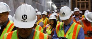 A large number of construction workers wearing protective head wear and safety vests.
