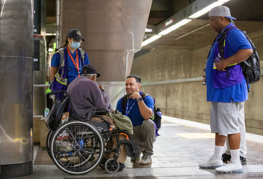 Metro Outreach Program team members talking with a person in a wheelchair on the station platfrom.