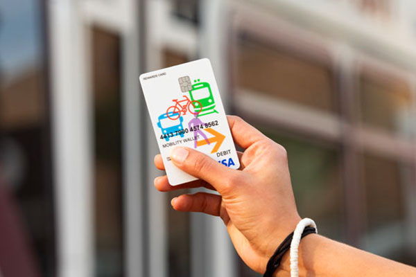 Person holding a Mobility Wallet Card in front of a Metro Bus.