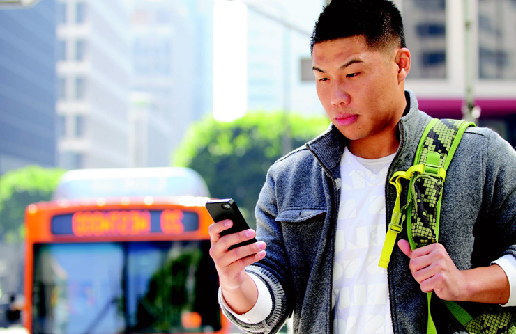 Metro rider using his phone while he waits for the bus